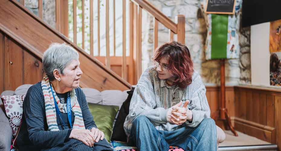 Member of chaplaincy staff sat on sofa talking to student