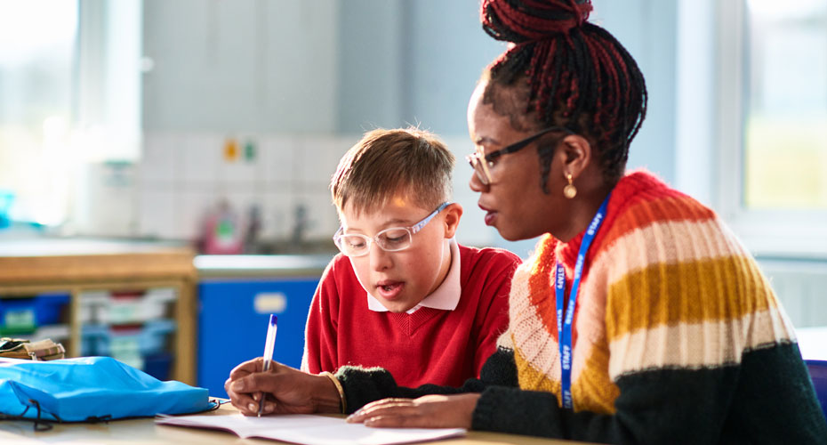A female teaching explaining something to a young school boy.