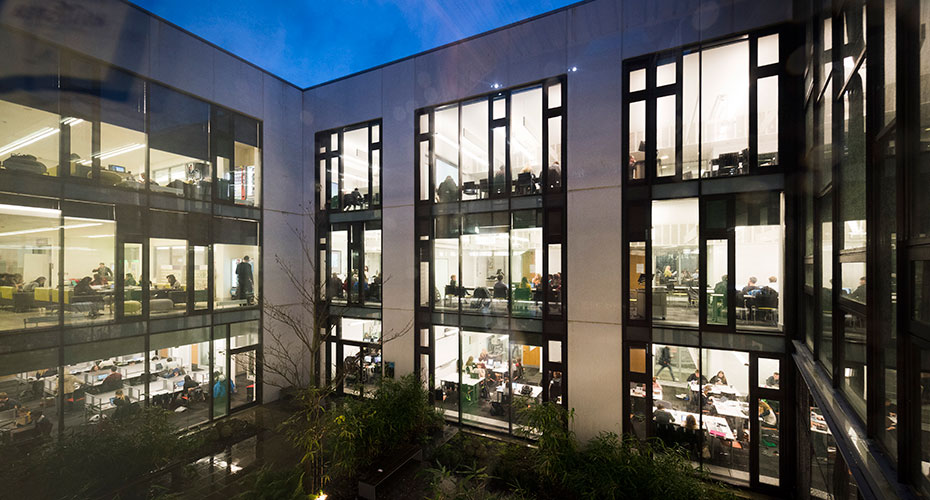 The Forum, Streatham Campus, at night. Students can be seen working in classrooms through the large windows