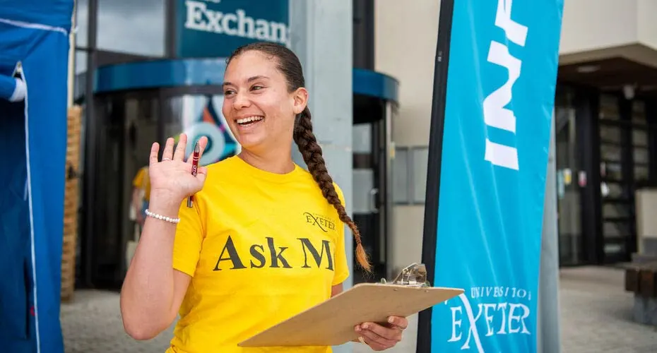 A student welcoming visitors outside the Exchange building on the Penryn Campus