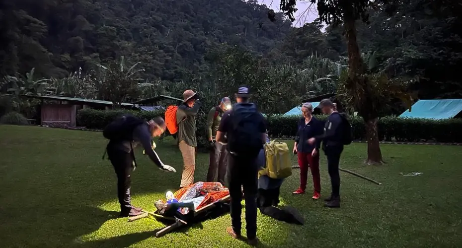 Extreme Medicine students gathered around a dummy patient in a rainforest environment at nightfall
