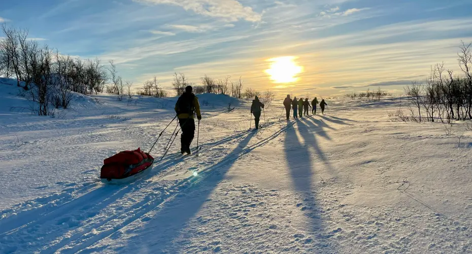 Group of MSc Extreme Medicine students walking on skis across a snowy landscape at sunrise