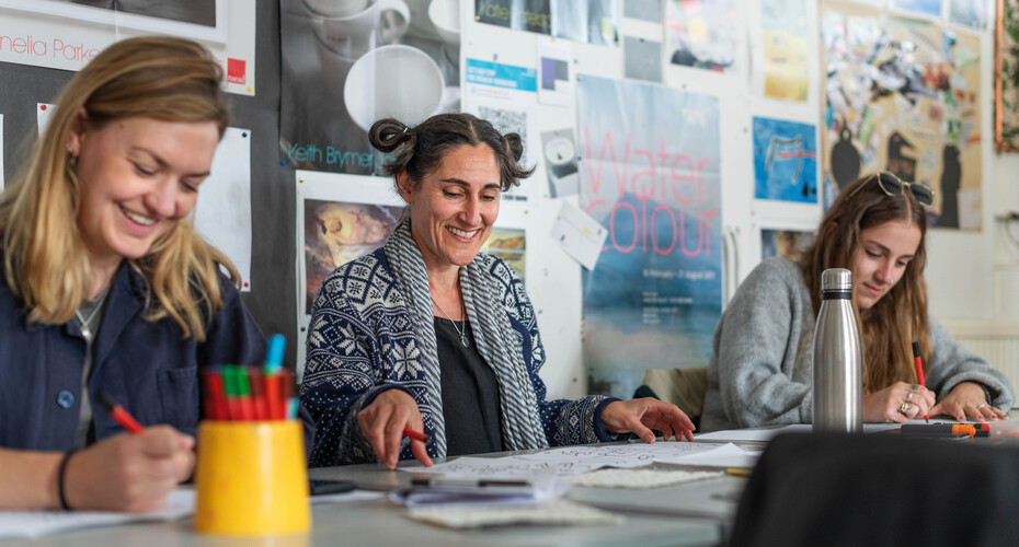 Three students working on art projects in a classroom