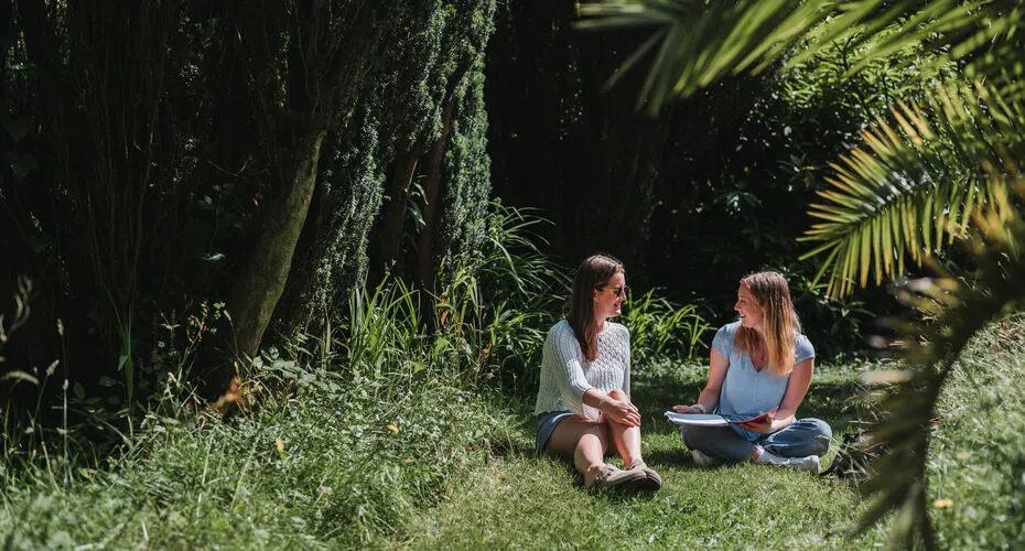 A pair of students studying together in an outdoors space on our beautiful Penryn Campus.